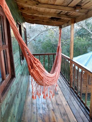 a hammock on a porch of a house at COEMBOTA Cabañas in Tigre