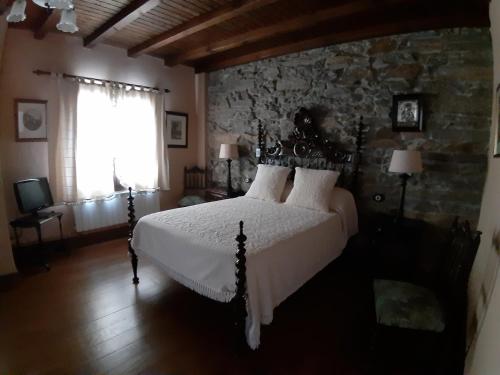 a bedroom with a bed and a stone wall at Casa Portela in Portela de Portomourisco