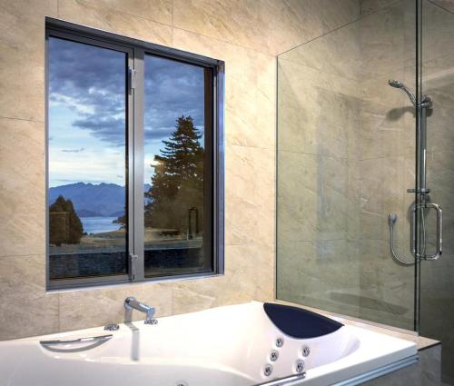 baño con ducha, lavabo y ventana en Golfcourse Road Chalets and Lodge en Wanaka