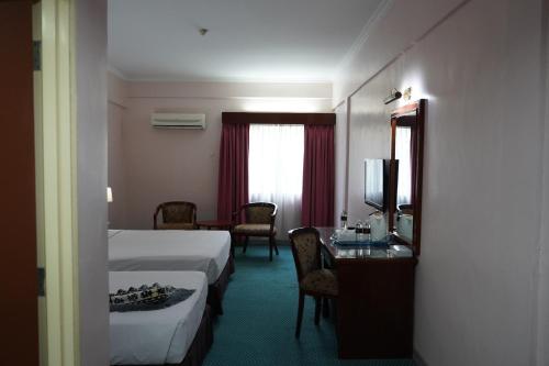 a hotel room with a bed and a table and a television at Hotel Seri Malaysia Johor Bahru in Johor Bahru