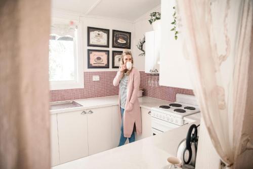 una mujer parada en una cocina hablando por teléfono en Jasmine's Barossa Valley Cottage en Lyndoch
