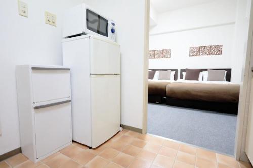a room with a refrigerator and a bed at Mansion Pasture TSUKISAMU Fukuzumi in Sapporo