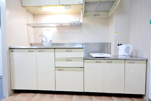 a kitchen with white cabinets and a sink at Mansion Pasture TSUKISAMU Fukuzumi in Sapporo