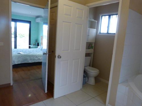 a white bathroom with a toilet and a bed at Le Médipole in Noumea
