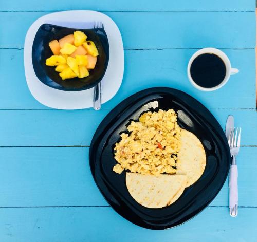 una mesa con un plato de comida y un bol de fruta en Playa del Ritmo Beach Hostel & Bar - Adults Only, en Santa Marta