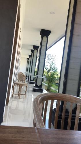 a porch with two wooden chairs and columns at Eva Guest House in Canggu