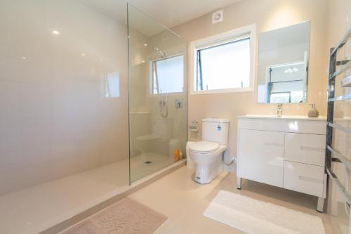 a bathroom with a toilet and a glass shower at Aroma House in Pokeno