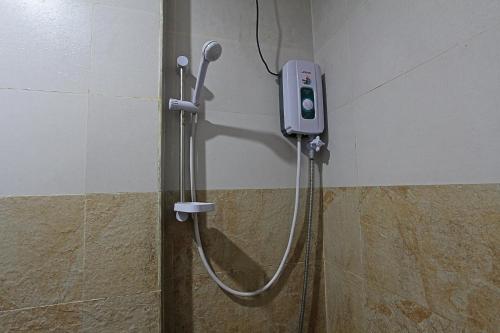 a shower in a bathroom with a phone on the wall at Seaslugs Traveller's Inn in El Nido