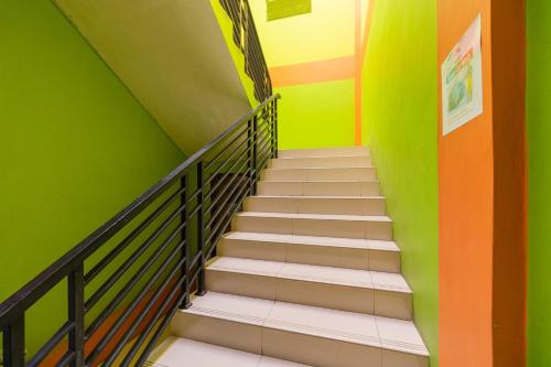 a staircase in a room with green and orange walls at RedDoorz near Kejaksan Station Cirebon 2 in Cirebon