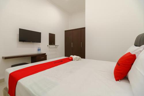 a bedroom with a white bed with red pillows at RedDoorz near Kejaksan Station Cirebon 2 in Cirebon