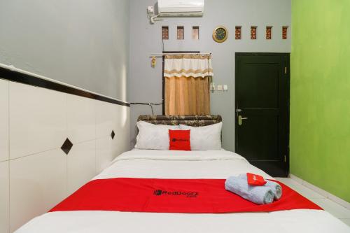 a bed with a red blanket and two towels on it at RedDoorz Syariah near Ciledug Station in Cirebon