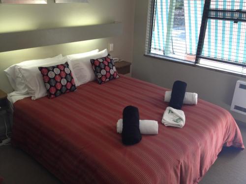 a bedroom with a large bed with towels on it at Black Forest Motel in Macedon