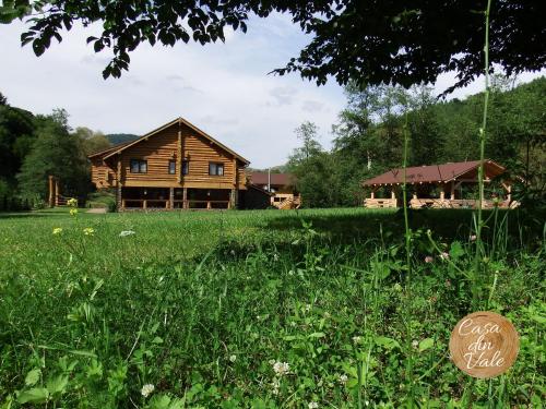 a log cabin in a field with a sign in the grass at Casa din Vale in Săcuieu