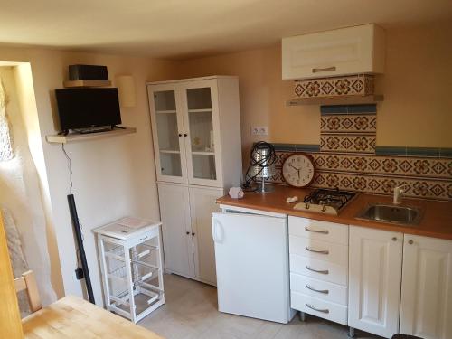 une cuisine avec des armoires blanches et un réfrigérateur blanc dans l'établissement Le pigeonnier de felines, à Caylus