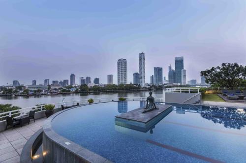 a statue in the middle of a pool with a city skyline at Chatrium Hotel Riverside Bangkok in Bangkok