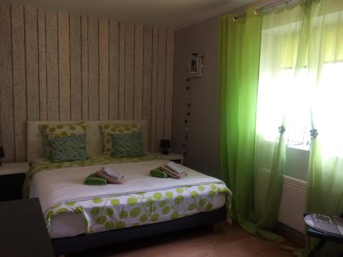 a bedroom with a bed with green curtains and a window at Villa Nature 02 in Meunet-sur-Vatan