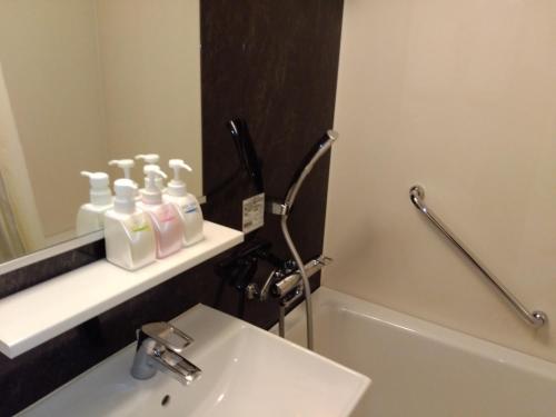 a bathroom with a sink and a toilet and a mirror at Hotel Sunlife in Osaka