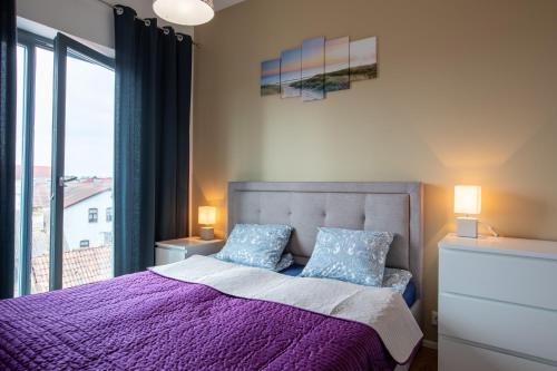 a bedroom with a purple bed with a large window at Katarina Apartments in Pärnu