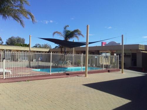a fence with a pool in front of a building at Desert Sand Motor Inn in Broken Hill