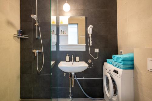 a bathroom with a shower and a sink and a washing machine at Katarina Apartments in Pärnu