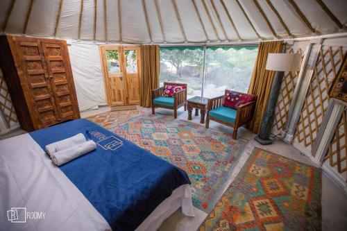 a bedroom with a bed and two chairs in a tent at Roomy Yurts, Minapin Nagar Hunza in Hini