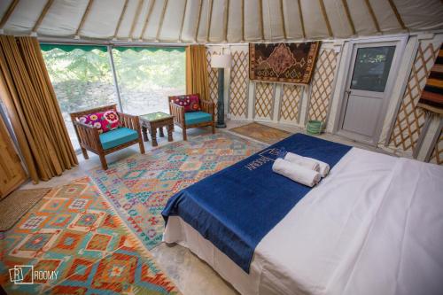 a bedroom with a bed and two chairs and windows at Roomy Yurts, Minapin Nagar Hunza in Hini