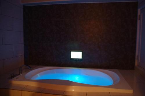 a bath tub in a bathroom with a tv on the wall at Hotel MINT Osaka Airport in Ikeda