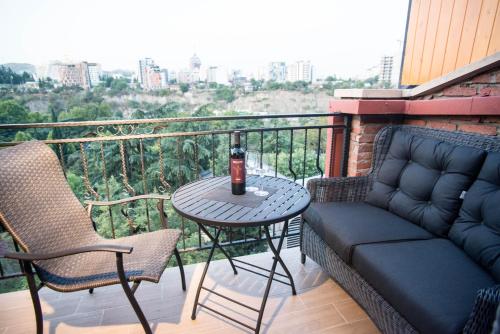 a table and chairs on a balcony with a drink on it at Hotel City Lights - Tbilisi in Tbilisi City