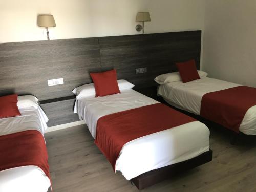 a hotel room with three beds with red pillows at Hotel Restaurante Santa Cruz in Santa Cruz de Mudela