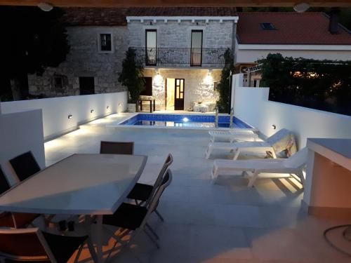een patio met een tafel en stoelen en een zwembad bij Villa Dragi in Klek