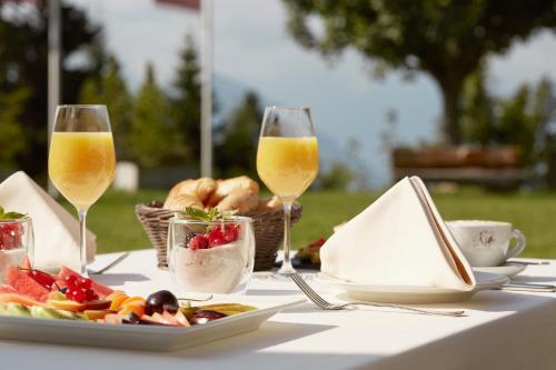 a table with a plate of food and two glasses of wine at Rigi Kaltbad Swiss Quality Hotel in Rigi Kaltbad