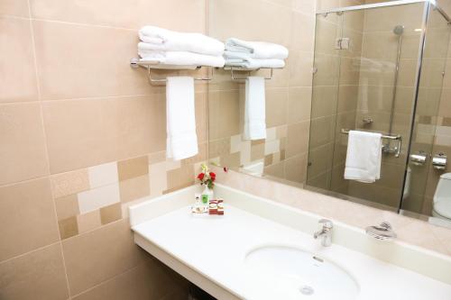a bathroom with a sink and a mirror and towels at Hotel One Rahim Yar Khan Club Road in Rahimyar Khan