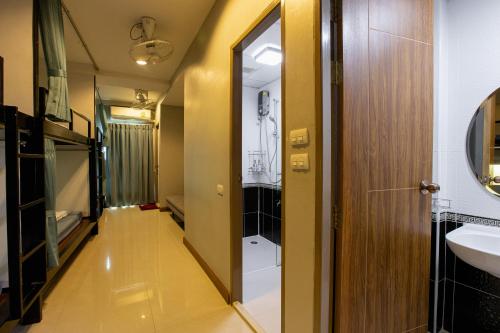 a hallway of a bathroom with a sink and a mirror at Restiny Hostel in Bangkok