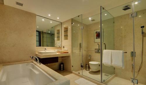 a bathroom with a tub and a sink and a shower at Hotel Platinum in Rajkot