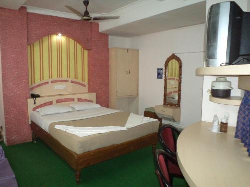 a bedroom with a bed and a table with chairs at Hotel Mahalaxmi Indo Myanmar in Guwahati