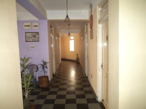 a hallway with a checkerboard floor and purple walls at Hotel Mahalaxmi Indo Myanmar in Guwahati