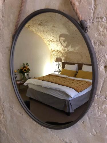 un miroir reflétant une chambre avec un lit dans une pièce dans l'établissement Chambre Troglodytique Villa Marie Louise, à Rochecorbon