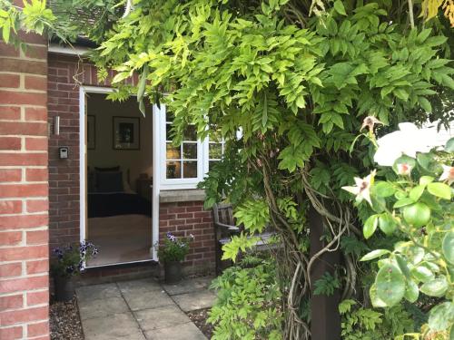 uma porta para uma casa de tijolos com uma árvore em Garden Room em Wallingford