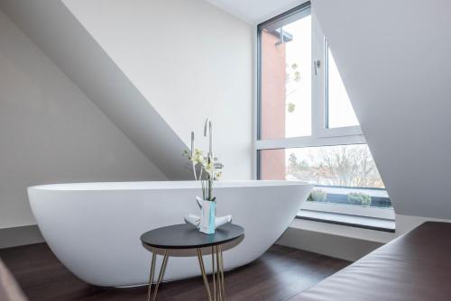 a bathroom with a large white bath tub and a table at Innspire Hotel in Munich