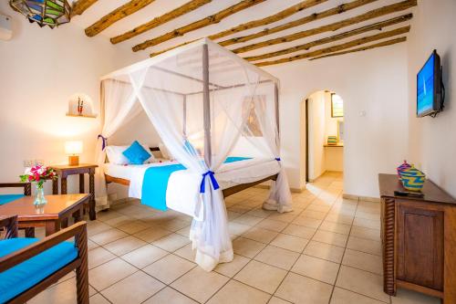 a bedroom with a bed with a canopy at Diani Sea Lodge - All Inclusive in Diani Beach