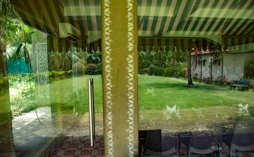a window with a view of a yard with a patio at Breathing Earth - Rooms and Pool in Kolkata