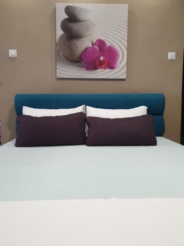 a bed with two pillows and a painting on the wall at Woodstone apartment in Ploieşti