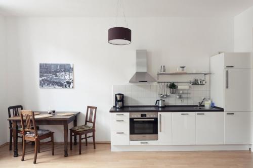 uma cozinha com armários brancos e uma mesa com cadeiras em Arbio I Spacious Apart in Center Leipzig em Leipzig