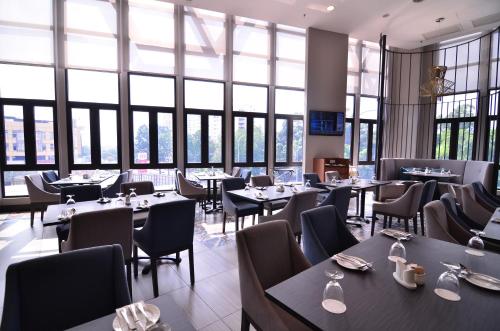 a restaurant with tables and chairs and large windows at Mercure Selangor Selayang in Batu Caves