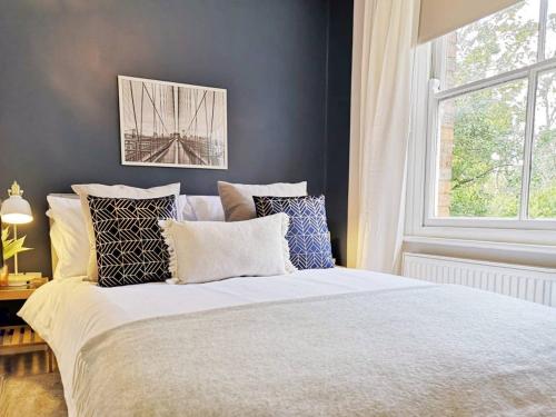 1 dormitorio con cama con almohadas y ventana en Bright, Charming & Peaceful Oxford Apartment, en Oxford