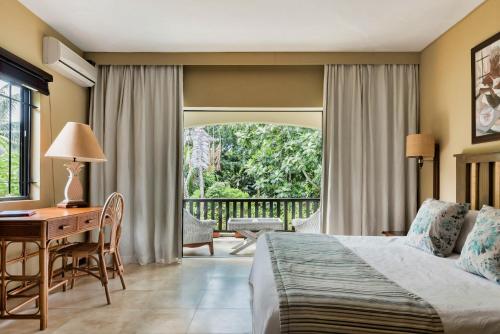 a hotel room with a bed and a desk and a window at Villa Vakoa - Tranquil Villa With Lush Gardens in Pointe d'Esny