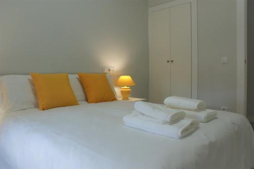 a white bed with orange and white pillows on it at Las Covachuelas (VuT) in Avila