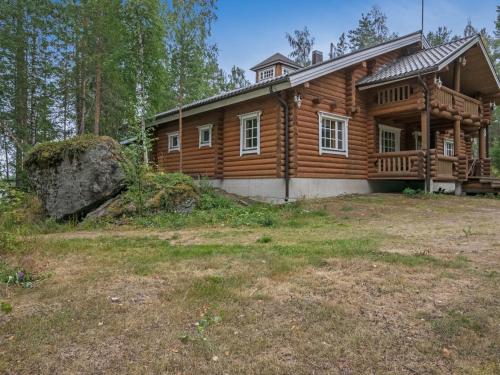 een blokhut met een grote rots ervoor bij Holiday Home Hiidenlinna by Interhome in Pitkälahti