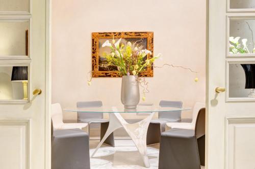 a dining room with a glass table and a vase with flowers at Alpi Hotel in Rome