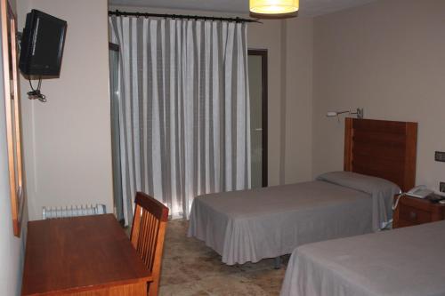 a hotel room with two beds and a table and a television at Hotel Peña Escrita in Fuencaliente
